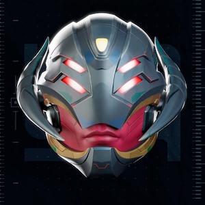 May include: A futuristic, metallic helmet with red glowing eye-like features and a red face. The helmet has a sleek, angular design with a prominent chin and cheek structure. The image includes the text "2020", "TEST PRINTED AMS COLORED STL", and "PATREON.COM/YOSHSTUDIOS".