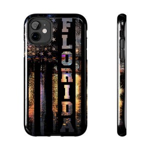 Puede incluir: Funda de teléfono negra con un diseño estilizado de la bandera estadounidense y la palabra "FLORIDA" en texto vertical blanco. La funda tiene un acabado brillante y un aspecto elegante y moderno.