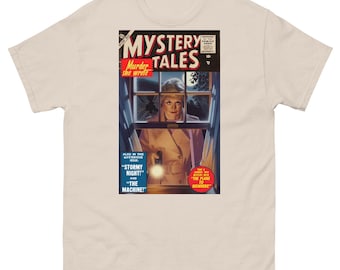 Op de afbeelding: Beige t-shirt met een vintage stripboekcover ontwerp. De cover leest "MYSTERY TALES" met "Murder she wrote" en andere tekst. De illustratie toont een vrouw in een trenchcoat met een zaklamp, omlijst door een raam.
