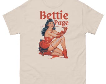 May include: A white t-shirt with a vintage illustration of Bettie Page in a red dress and red heels. The text "Bettie Page" is printed in a bold, gothic font.