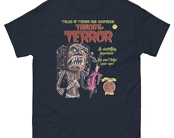 May include: A navy blue t-shirt with a vintage-style illustration of a monster holding a spear. The text on the shirt reads "TALES OF TERROR AND SUSPENSE TRILOGYor TERROR An electrifying Experience You won't believe your eyes! FEATURING"