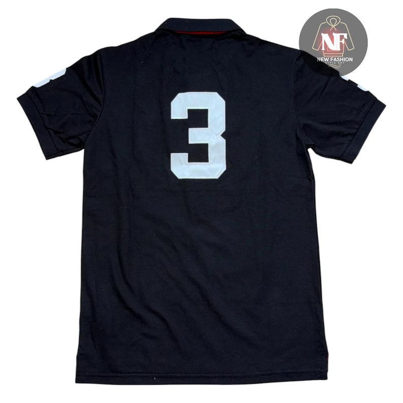 May include: Black polo shirt with a white number 3 on the back. The shirt has short sleeves and a collared neckline. The number 3 is large and centered on the back of the shirt.