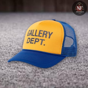 May include: A blue and yellow trucker hat with the text "GALLERY DEPT." in dark blue. The hat has a mesh back and a curved brim. The hat is a stylish accessory.