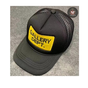May include: Black trucker hat with a mesh back and a curved brim. The front features a yellow rectangular patch with the words "GALLERY DEPT." in black. A small logo is visible on the side.