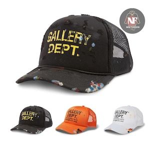 Puede incluir: Gorra de camionero negra con el texto "GALLERY DEPT." en amarillo. La gorra tiene una parte trasera de malla y una visera curva. La gorra tiene un diseño de salpicaduras de pintura en varios colores. También se muestran gorras adicionales en naranja y blanco.