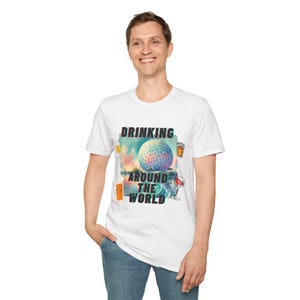 May include: White t-shirt with a colourful graphic design featuring a globe, palm trees, and drinks. The text "Drinking Around The World" is printed on the shirt.
