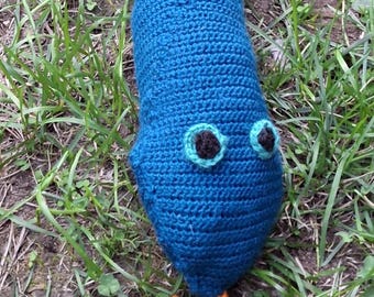 May include: A long, stuffed crochet snake toy featuring a primary dark blue body with a pattern of diamond-shaped patches in light blue, pink, yellow, and green. The snake has two black and light blue eyes and a small orange forked tongue.