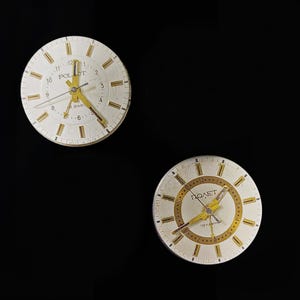 May include: Two vintage Poljot wristwatches with white faces, gold hands, and hour markers. The watch faces display the brand name and the word "Jewels". The watches are set against a black background.