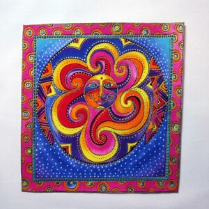 May include: Square fabric art featuring a colorful sun design. The sun has a face with blue eyes and a smiling mouth, surrounded by swirling red, orange, and yellow rays. The artwork is framed with a pink border.