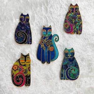 May include: Five decorative cat figurines with intricate patterns and vibrant colors. Each cat features a unique design, including floral and swirling motifs, with a gold outline. The cats are in shades of blue, yellow, and pink.