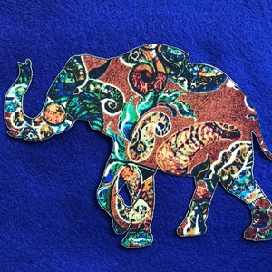 May include: A colourful patterned elephant silhouette cut out of fabric. The elephant is brown with green, blue and yellow paisley patterns.