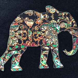 May include: A black fabric elephant silhouette with a paisley pattern in shades of green, orange, and gold.
