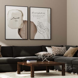 May include: Two framed prints with a white background and brown accents. The left print features the Arabic word "Sabr" in a brown circle with a white outline. The right print features a line drawing of two hands in a prayer position with the Arabic text "وَقَالَ رَبُّكُمُ ادْعُونِي أَسْتَجِبْ لَكُمْ" and the English translation "AND YOUR LORD SAYS, 'CALL UPON ME, I WILL RESPOND TO YOU.'"