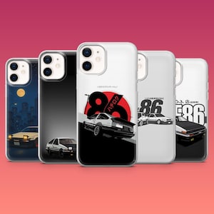 May include: A collection of phone cases featuring car designs. One case shows a car driving at night, while others display stylized car illustrations with Japanese text and the number 86. The cases are white, black, and clear.