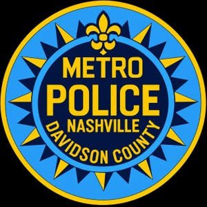 May include: A circular emblem featuring a dark blue center with the yellow text METRO POLICE NASHVILLE DAVIDSON COUNTY and a yellow fleur-de-lis at the top. The border consists of alternating light blue and yellow triangular points on a blue ring.
