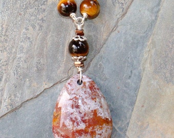 May include: A silver chain necklace with a teardrop-shaped pendant made of red and white agate. The necklace is adorned with tiger's eye beads.
