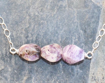 May include: A silver chain necklace with three purple and white gemstone beads.