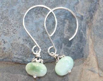 May include: A pair of silver dangle earrings with light green oval-shaped stones.