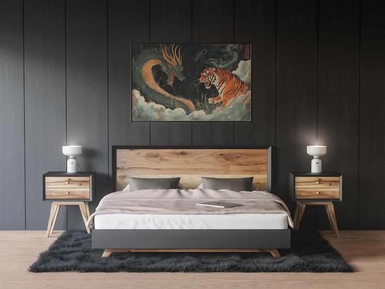 K&ouml;nnte beinhalten: Ein Schlafzimmer mit einem Holzbettgestell und einem schwarzen Kopfteil. Das Bett hat eine wei&szlig;e Bettdecke und zwei graue Kissen. An beiden Seiten des Bettes stehen zwei Nachttische mit Lampen. Ein gerahmtes Bild eines gr&uuml;nen Drachen und eines Tigers, die sich gegen&uuml;berstehen, h&auml;ngt an der Wand &uuml;ber dem Kopfteil.