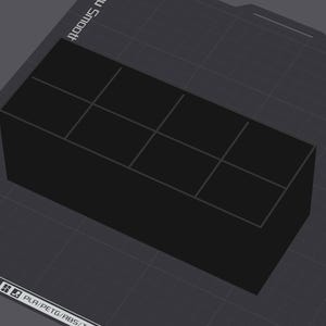 May include: A black rectangular object with a grid pattern on top, possibly a 3D-printed part. The object is on a dark gray surface with the text "amp Plate" and "PLA/PETG/ABS/T" visible.
