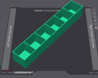 May include: A 3D-rendered, green rectangular organizer with five compartments. The text "Bambu Textured PE" is visible. The organizer is on a dark grey surface with text indicating "Left nozzle only area" and "Right nozzle only area".