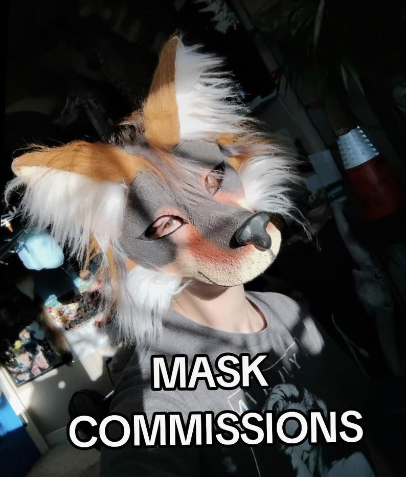 May include: A close-up of a furry fox mask with brown, white, and gray fur. The mask has a black nose and is worn by a person wearing a gray t-shirt. The text "MASK COMMISSIONS" is displayed in white letters.