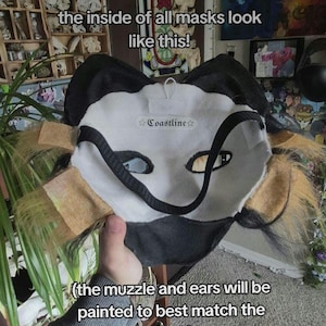 May include: A handmade mask with a white face, black accents, and tan fur details. The text "the inside of all masks look like this!" and "Coastline" are visible. The muzzle and ears will be painted to match the mask.