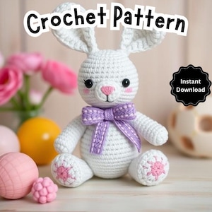 May include: White crocheted bunny rabbit with purple bow, sitting on a white surface. The bunny has pink cheeks and a pink nose. The image includes the text "Crochet Pattern" and "Instant Download".