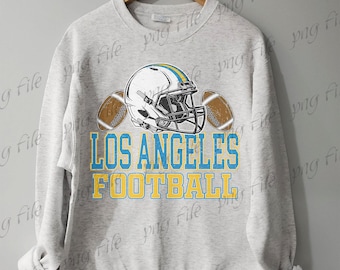 Op de afbeelding: Een lichtgrijs sweatshirt met een footballhelm en twee ballen. De tekst "LOS ANGELES FOOTBALL" is gedrukt in blauw en geel. Het sweatshirt hangt aan een houten hanger.