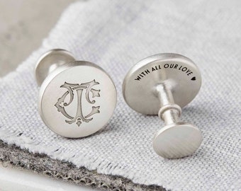 Puede incluir: Gemelos de plata con un monograma grabado en un lado y el texto "With all our love" en el otro.