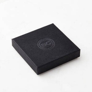 May include: A black square box with a raised, circular logo in the centre. The logo is a stylised letter "C" inside a circle.