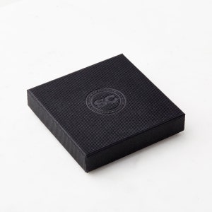 Op de afbeelding: Zwarte vierkante doos met een reli&euml;flogo met de tekst "Handmade in Ireland" en "SC" in een cirkel.