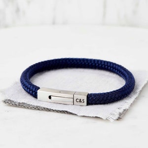 Op de afbeelding: Een gevlochten armband in marineblauw met een zilveren sluiting en gegraveerde initialen "C&S".