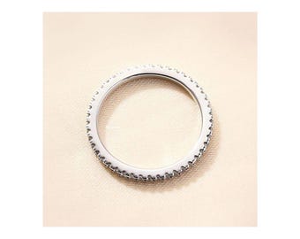 May include: A silver ring with a row of small, clear stones around the band.