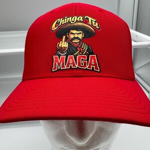 Può includere: Cappellino da baseball rosso con una grafica di un uomo con il sombrero che fa il dito medio. Il testo "Chinga Tu" e "MAGA" sono visualizzati in oro e rosso.