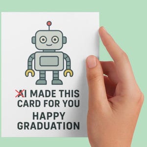 May include: A white graduation card featuring a cartoon robot with a red antenna, gray body, and yellow hands and feet. The card reads "I MADE THIS CARD FOR YOU HAPPY GRADUATION" in black text.