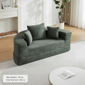 May include: A green corduroy sofa with three matching throw pillows. The sofa has a rounded shape and is placed on a light-colored rug. The total diameter is 180 cm.