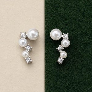 May include: A pair of silver-toned ear climbers featuring a curved arrangement of alternating white round pearls and clear sparkling cubic zirconia stones. Each earring follows a linear, ascending design that highlights the contrast of textures.