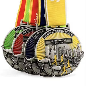 Puede incluir: Una colección de medallas plateadas de la serie Qatar Running con cintas coloridas. Cada medalla presenta un paisaje urbano, corredores y camellos. Las medallas tienen detalles verdes, rojos, azules y amarillos, con el texto "Summer Sizzler".