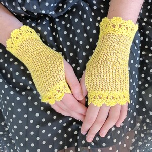 May include: A pair of bright yellow fingerless gloves featuring a delicate, intricate crochet lace trim at both the top and bottom edges. The main body of the gloves is crafted from a fine, lightweight knit fabric with a subtle, semi-sheer texture.