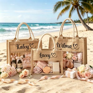 May include: Three jute tote bags with clear front panels, personalized with names and hearts, filled with gifts. The bags sit on a sandy beach with flowers and ribbons. The names "Kaley", "Lacey", and "Wilma" are visible.