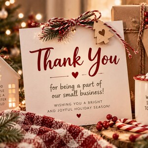 K&ouml;nnte beinhalten: Eine wei&szlig;e quadratische Karte mit rotem und schwarzem Text, der lautet: Thank You for being a part of our small business! WISHING YOU A BRIGHT AND JOYFUL HOLIDAY SEASON! Die Karte ist mit einer rot-wei&szlig;en Kordelschleife und einem kleinen Holzbaum verziert.