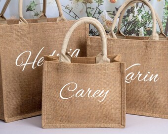 May include: Three brown burlap tote bags with white lettering. The bags are different sizes and have the names "Carey", "Erin", and "Wedding" written on them.