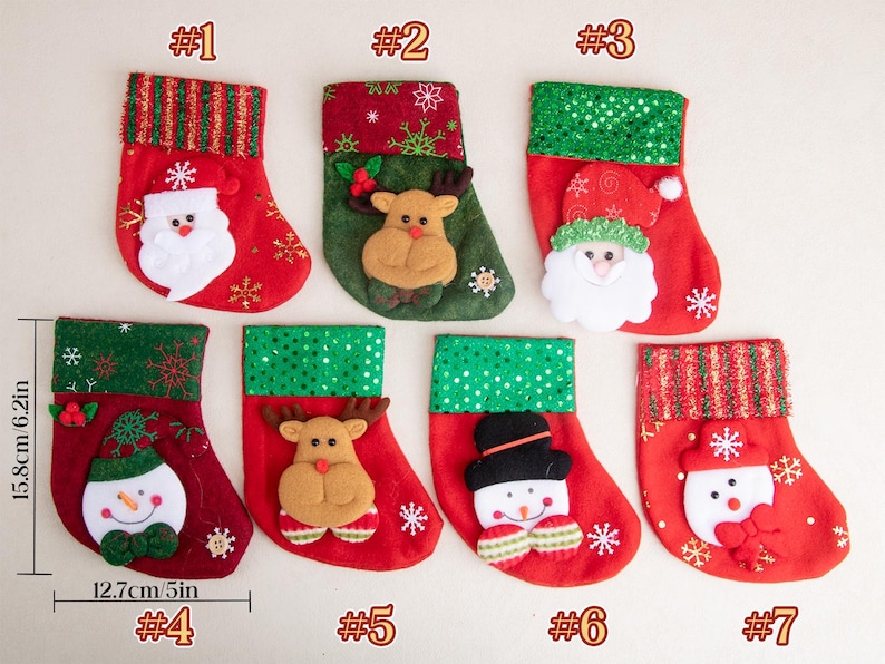 K&ouml;nnte beinhalten: Sieben Weihnachtsstr&uuml;mpfe, nummeriert von 1 bis 7, mit einer Gr&ouml;&szlig;e von jeweils 15,8 cm mal 12,7 cm. Die Str&uuml;mpfe zeigen festliche Motive wie den Weihnachtsmann, Rentiere und Schneem&auml;nner, verziert mit rotem und gr&uuml;nem Stoff, Glitzer und Schneeflocken.