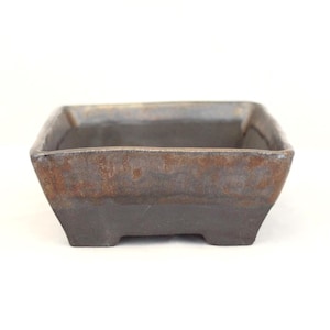 May include: A square, dark brown ceramic bonsai pot with a textured surface. The pot has a slightly flared shape and sits on four small feet. The rim has a lighter, metallic-like finish.