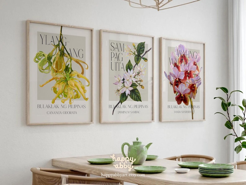 Może przedstawiać: Trzy oprawione grafiki botaniczne z ilustracjami kwiatowymi. Grafiki przedstawiają ż&oacute;łte, białe i fioletowe kwiaty, każda z tekstem w obcym języku. Grafiki są wyświetlane nad drewnianym stołem z zielonymi talerzami i imbrykiem.