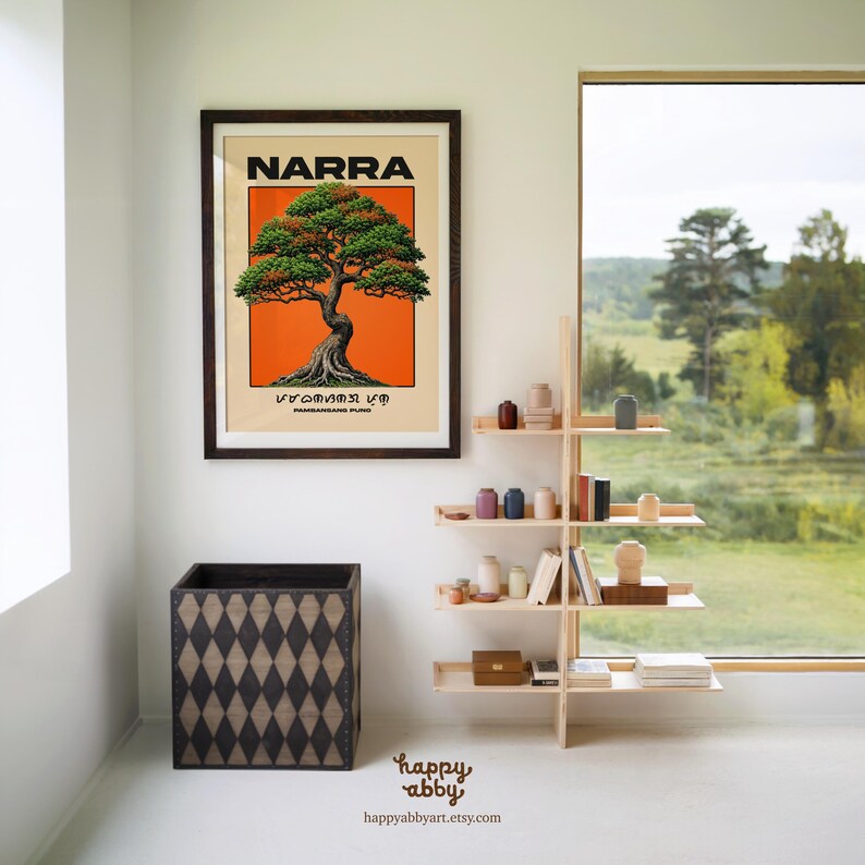 Puede incluir: Una l&aacute;mina enmarcada con una ilustraci&oacute;n estilizada de un &aacute;rbol Narra sobre un fondo naranja vibrante, con el texto "NARRA" y "PAMBANSANG PUNO" en negro, situada sobre un contenedor de madera oscura con patr&oacute;n de rombos y una estanter&iacute;a.