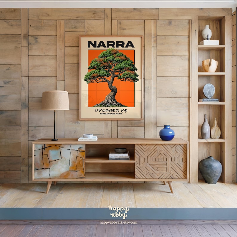 Puede incluir: Un p&oacute;ster de pared rectangular que presenta una ilustraci&oacute;n detallada de un &aacute;rbol Narra con follaje verde y un tronco texturizado sobre un fondo naranja s&oacute;lido, con el texto NARRA y escritura Baybayin impresos en negro sobre y bajo el &aacute;rbol.
