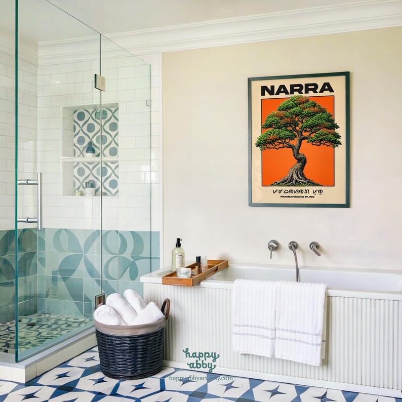 Puede incluir: Una l&aacute;mina de arte mural enmarcada titulada NARRA que presenta una ilustraci&oacute;n detallada de un &aacute;rbol sobre un fondo naranja vibrante. La obra de arte se muestra en una pared clara sobre una ba&ntilde;era blanca con dos toallas blancas sobre el borde.