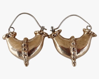 May include: A pair of gold hoop earrings with a unique design. The earrings are made of a smooth, shiny metal and have a curved, organic shape. The hoops are attached to a silver wire.